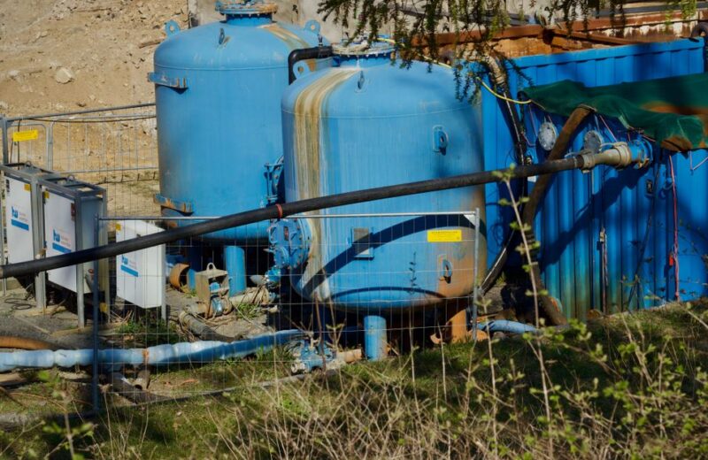 Large mineral tanks and blue plumbing at a water treatment installation representing softener regeneration hardware